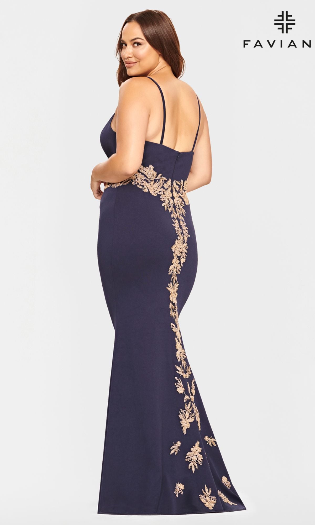 A woman in the Navy and Gold Plus-Size Faviana Prom Dress 9540 faces away, glancing back. The gown features thin straps, gold floral embroidery, and a flattering mermaid silhouette for an elegant prom look.